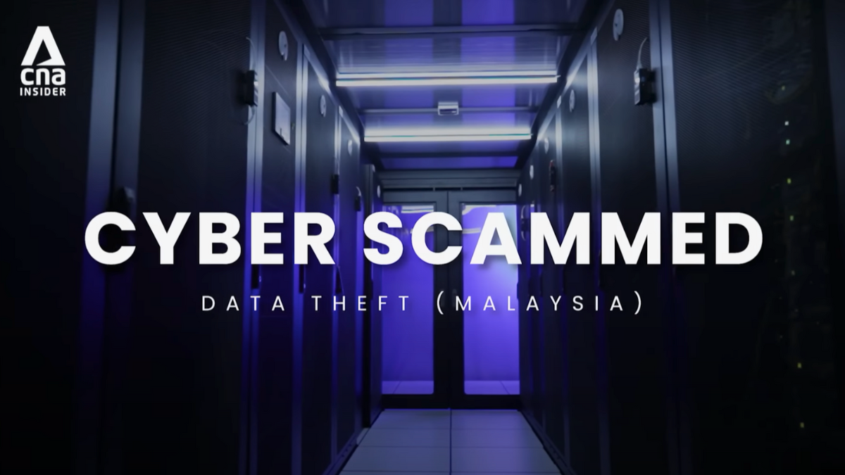 A dimly lit server room with rows of black cabinets illuminated by blue and purple lighting. Large white text overlay reads 'CYBER SCAMMED' with a subtitle below stating 'DATA THEFT (MALAYSIA),' suggesting a focus on cybersecurity threats.